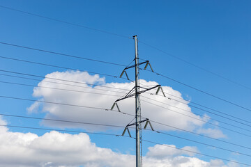 High-voltage power line against the background of clouds and blue sky.