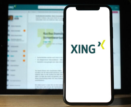 XING Logo wird auf modernem Smartphone angezeigt, im Hintergrund ein Bildschirm welcher ein XING Nutzerprofil anzeigt, Soziale Netzwerke, 2023