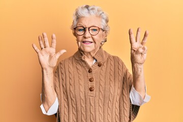 Senior grey-haired woman wearing casual clothes and glasses showing and pointing up with fingers number eight while smiling confident and happy.