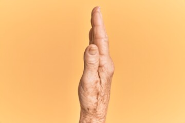 Senior caucasian hand over yellow isolated background showing the side of stretched hand, pushing...