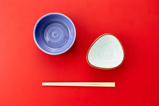 Empty food bowls with chopsticks on red background