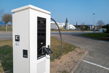 in the parking lot there is a white charging station electric cars