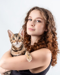 Young beautiful woman with bengal cat in hands isolated on white background. Pet and owner portrait