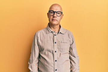 Obraz premium Middle age bald man wearing casual clothes and glasses relaxed with serious expression on face. simple and natural looking at the camera.