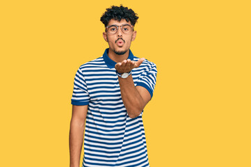 Young arab man wearing casual clothes and glasses looking at the camera blowing a kiss with hand on air being lovely and sexy. love expression.