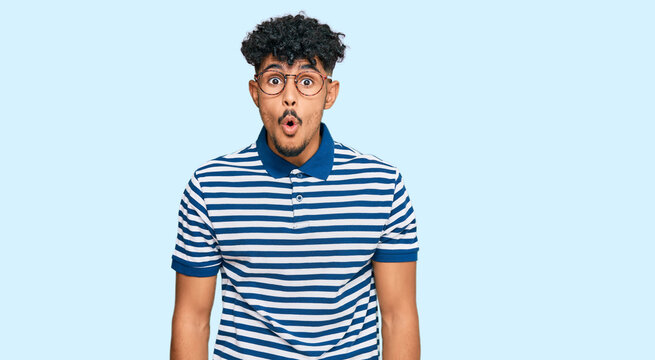 Young arab man wearing casual clothes and glasses afraid and shocked with surprise expression, fear and excited face.