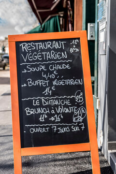 A French bistro menu sign on a blackboard written in white chalk on an orange stand.Found in Paris France.