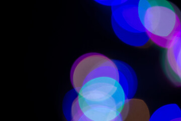 Defocused image of multicolored circles on an abstract background. Dark background, blur bokeh.