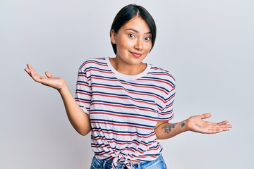 Beautiful young woman with short hair wearing casual clothes clueless and confused expression with arms and hands raised. doubt concept.