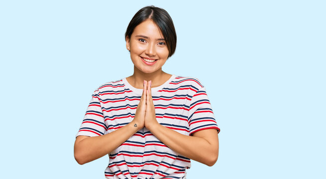 Beautiful young woman with short hair wearing casual clothes praying with hands together asking for forgiveness smiling confident.