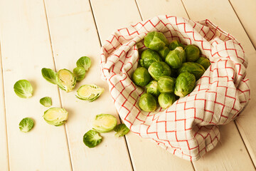 Bunch of fresh raw Brussel sprouts in fabric towel on a white wood table