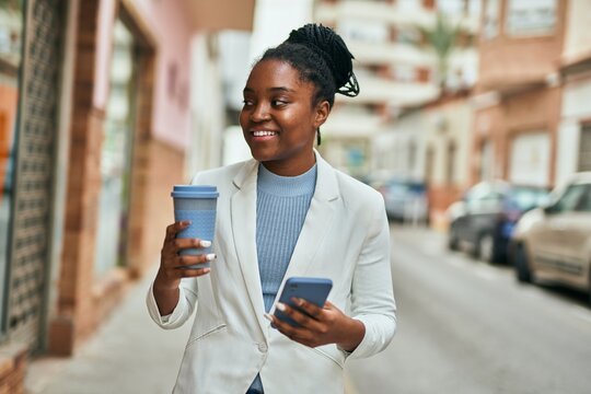 Young african american businesswoman using smartphone and drinking coffee at the city.