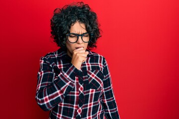 Fototapeta na wymiar Young hispanic woman with curly hair wearing casual clothes and glasses feeling unwell and coughing as symptom for cold or bronchitis. health care concept.
