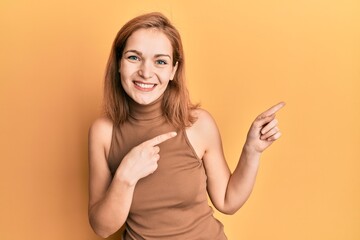 Young caucasian woman wearing casual style with sleeveless dress smiling and looking at the camera pointing with two hands and fingers to the side.