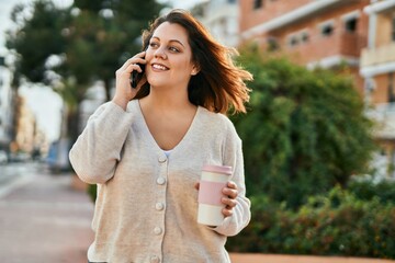 Young irish plus size girl talking on the smartphone and drinking coffee at the city.