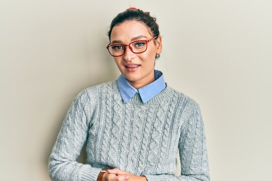 Young caucasian woman wearing casual clothes and glasses with hands together and crossed fingers smiling relaxed and cheerful. success and optimistic
