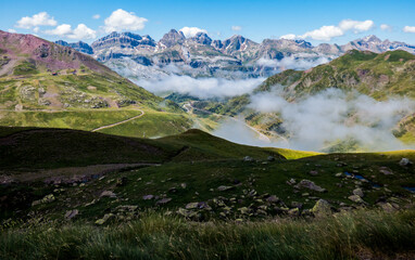 Fototapeta na wymiar Piedras y praderas de alta montaña con las altas cumbres de los Pirineos españoles al fondo