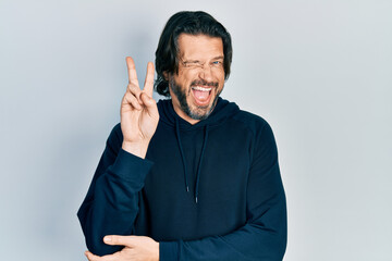 Middle age caucasian man wearing casual sweatshirt smiling with happy face winking at the camera...