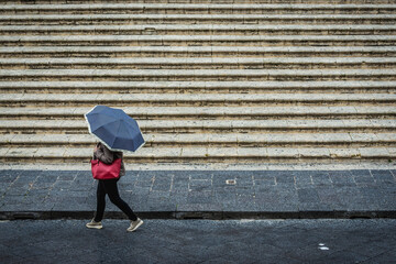 woman passes next to stairs in front of Roman Catholic cathedral in historic part of Noto city,...