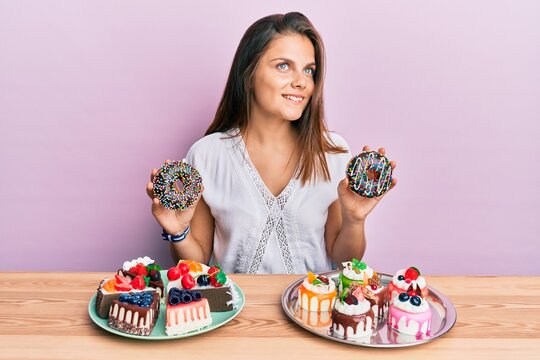 Young caucasian woman eating pastries for breakfast smiling looking to the side and staring away thinking.