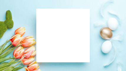 Easter eggs Golden color in basket with spring tulips, white feathers on pastel blue background in Happy Easter decoration. Festive decoration in flat lay.
