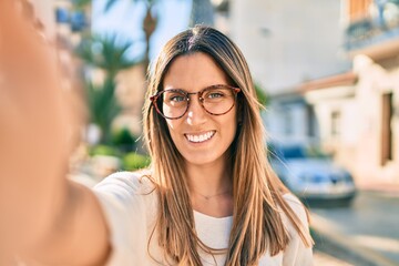 Young caucasian woman smiling happy making selfie by the camera at the city.