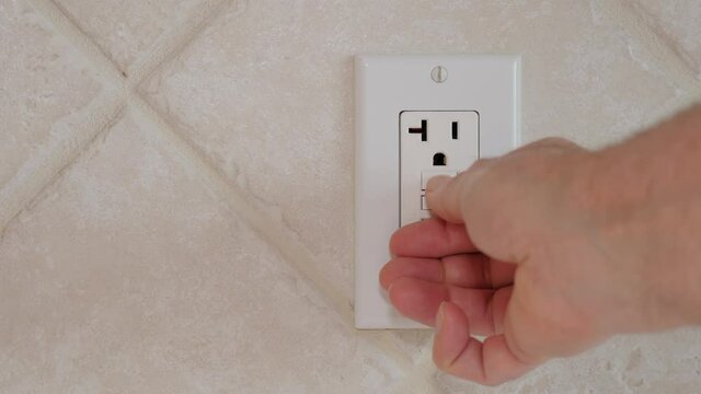 Testing and resetting GFCI ground fault interrupter electricity receptacle and wall plate. Residential electric plug with GFI reset button.