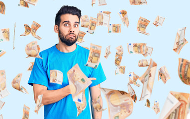 Young handsome man with beard wearing casual t-shirt pointing aside worried and nervous with...