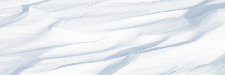 Obraz premium Beautiful winter background with snowy ground. Natural snow texture. Wind sculpted patterns on snow surface. Arctic, Polar region.