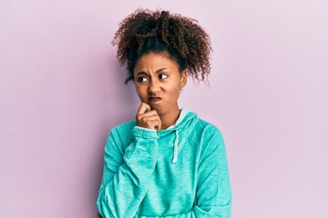 Fototapeta na wymiar Beautiful african american woman with afro hair wearing casual sweatshirt serious face thinking about question with hand on chin, thoughtful about confusing idea