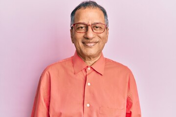 Obraz premium Middle age indian man wearing casual clothes and glasses relaxed with serious expression on face. simple and natural looking at the camera.