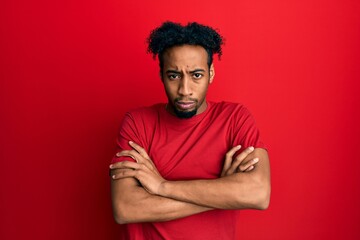 Fototapeta na wymiar Young african american man with beard wearing casual red t shirt skeptic and nervous, disapproving expression on face with crossed arms. negative person.