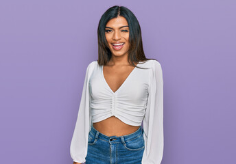 Young latin transsexual transgender woman wearing casual clothes winking looking at the camera with...