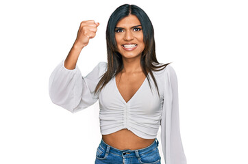 Young latin transsexual transgender woman wearing casual clothes angry and mad raising fist frustrated and furious while shouting with anger. rage and aggressive concept.
