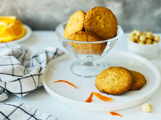  cookies in a vase, nuts and an orange on the table