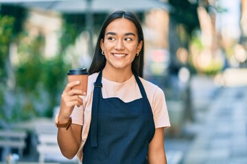 Young latin barista girl smiling happy holding take away coffee at the cafe shop