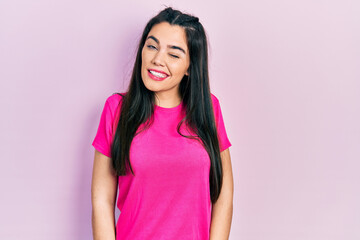 Fototapeta premium Young hispanic girl wearing casual pink t shirt winking looking at the camera with sexy expression, cheerful and happy face.