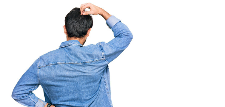 Young hispanic man wearing casual clothes backwards thinking about doubt with hand on head