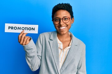 Young african american girl holding sale poster looking positive and happy standing and smiling with a confident smile showing teeth