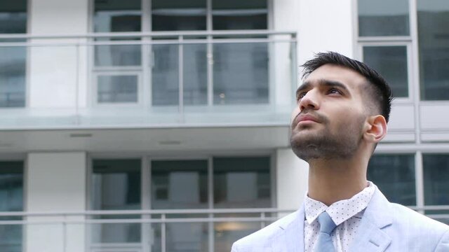 空、もしくはビルを見上げるスーツを着たインド人ビジネスマン