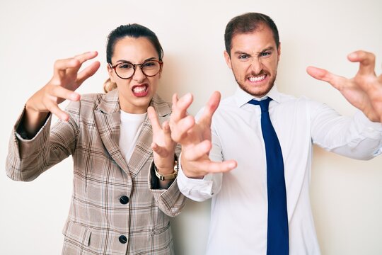 Beautiful couple wearing business clothes shouting frustrated with rage, hands trying to strangle, yelling mad
