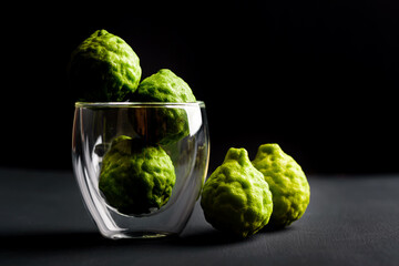 Fresh bergamot fruit in a glass on black background, Organic herbal and food ingredient