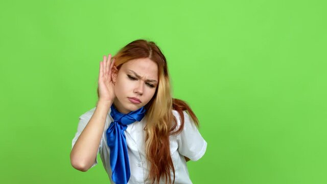 Young blonde teenager girl with stewardess uniform listening to something by putting hand on the ear over isolated background. Green screen chroma key