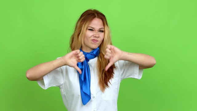 Young blonde teenager girl with stewardess uniform doing bad signal over isolated background. Green screen chroma key