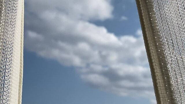 揺れるカーテンの間から見える空