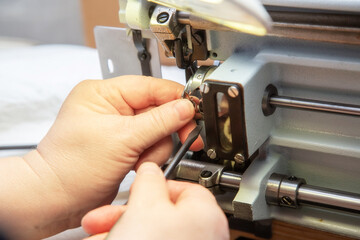 Fototapeta na wymiar Female hands with a screwdriver repair the shuttle of the sewing machine.