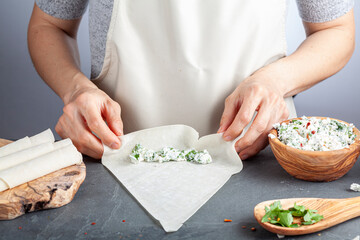 A caucasian woman is filling phyllo dough sheets known as yufka with cheese stuffing to make traditional Turkish sigara boregi (cigarette borek) a sort of deep fried rolls.