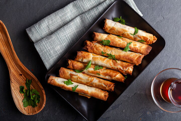 Traditional Turkish sigara boregi, a phyllo dough roll with cheese or ground meat stuffing. Deep fried rolls are served on a tray with parsley leaves as topping and Turkish tea on the side.