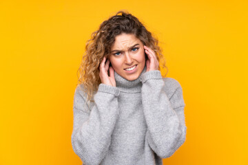 Young blonde woman with curly hair wearing a turtleneck sweater isolated on yellow background...
