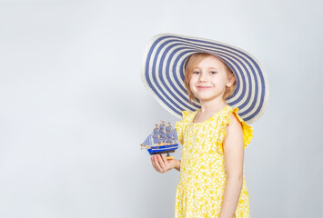 A girl in a wide-brimmed hat holds a toy boat in her hands.